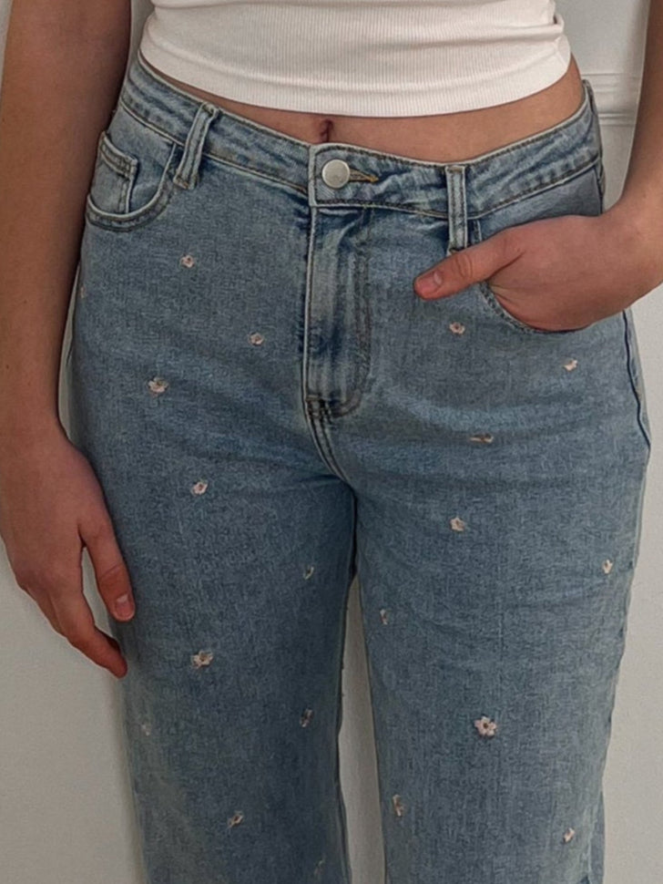 Frau mit Jeans, die ein rosanes Blumenmuster hat